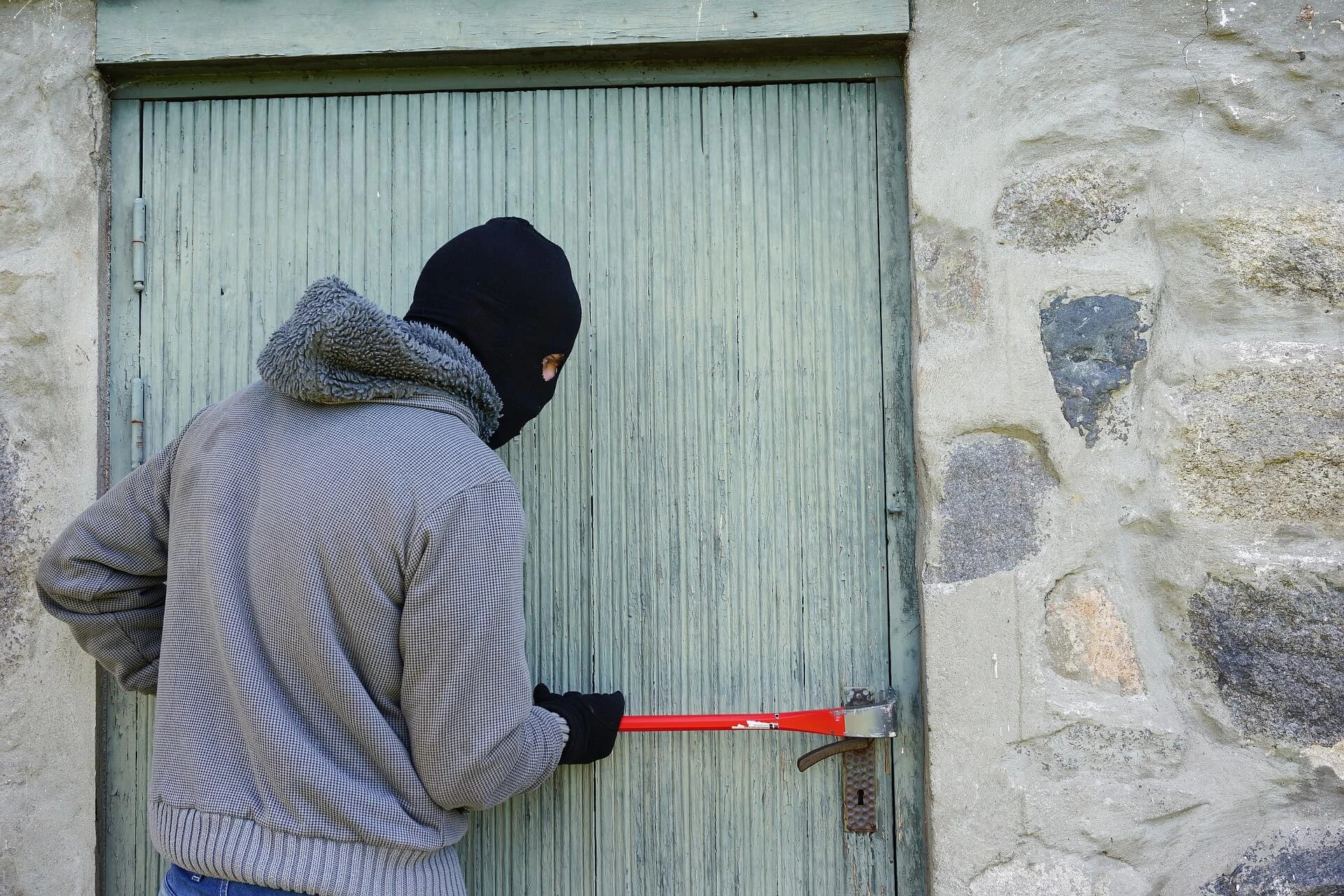Krisenklar - Ein vermummter Mann versucht mit einer Brechstange ein Tür aufzubrechen.